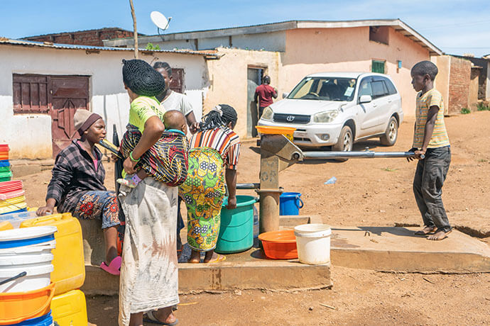 Women and children draw water from a borehole at Dzaleka Refugee Camp in Malawi. Resurrection, a multi-site United Methodist church in the Kansas City area, is supporting a program at the camp that provides sustenance and spiritual encouragement to refugees, many of whom are facing food insecurity and malnutrition. The church funded the borehole 10 years ago to provide clean water to the camp. Photo by Francis Nkhoma, UM News.