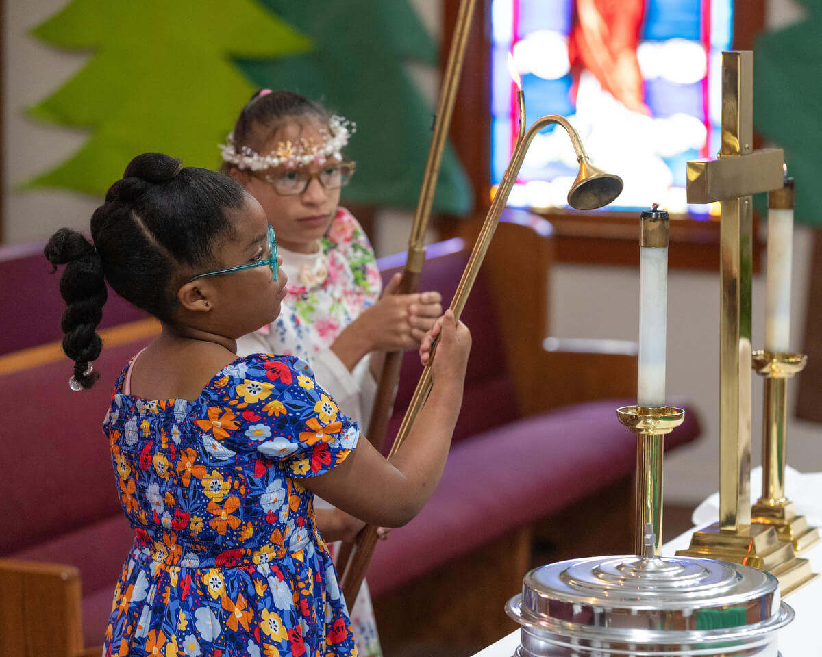 Acolytes Janae Williams (left) and Espn’ian Keys extinguish the candles following worship at Hartzell Mt. Zion United Methodist Church.
