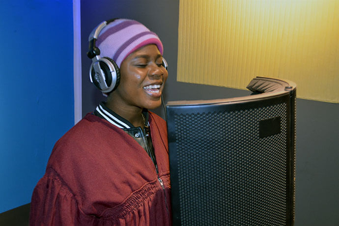 Belodie Musombu chante pendant une session d'enregistrement dans le nouveau studio de l'Eglise Méthodiste Unie Jerusalem, dans le Sud du Congo. Musombu est membre de la Chorale Méthodiste Unie Nouvelle Alliance, qui a récolté près de 50 000 dollars pour construire ce studio d'enregistrement moderne. Celui-ci comprend une cabine insonorisée, des microphones de haute qualité et d'autres équipements. Photo de Jenovic Mandandj, UM News.