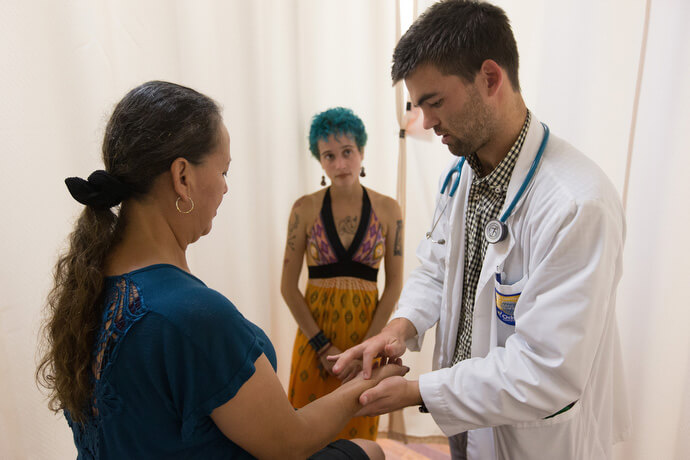 Medical student Joseph Pummer (right) examines a patient during a free medical clinic at Luke's House in 2015. At center, helping with Spanish translation, is Paloma Ellis, a public health practicum student from Tulane University. Photo by Mike DuBose, UM News.